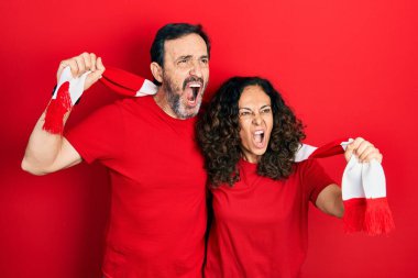 Orta yaşlı bir çift İspanyol kadın ve erkek eşarp takan futbol holiganları tezahürat yapıyor kızgın ve öfkeli çığlıklar atıyor, öfkeyle bağırıyor. öfke ve agresif konsept. 