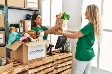 İki gönüllü kadın, hayır kurumunda çalışmaktan mutlu gülümsüyor..