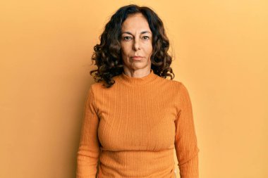 Orta yaşlı İspanyol kadın, günlük giysiler giyiyor, depresyonda ve endişe içinde, kızgın ve korkmuş bir şekilde ağlıyor. hüzünlü ifade. 