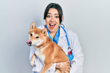 Güzel İspanyol veteriner kadın köpeğini kucağında tutuyor çılgınlığı kutluyor ve başarıya hayret ediyor gözleri açık heyecanla haykırıyor. 