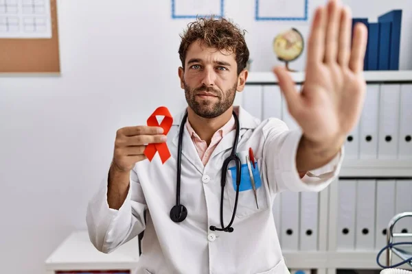 Joven Médico Hispano Sosteniendo Cinta Roja Apoyo Clínica Médica Con — Foto de Stock