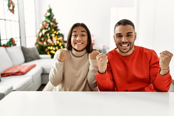 Jong Hispanic Paar Zitten Tafel Door Kerstboom Schreeuwen Trots Vieren — Stockfoto