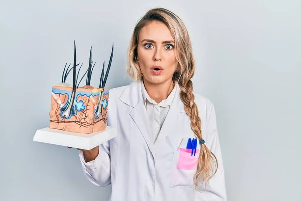 Linda Jovem Loira Segurando Modelo Pele Anatômica Cabelo Assustado Surpreso — Fotografia de Stock