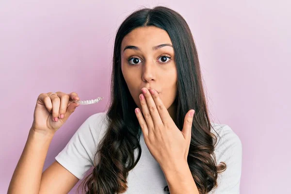 Young Hispanic Woman Holding Invisible Aligner Orthodontic Covering Mouth Hand — 스톡 사진