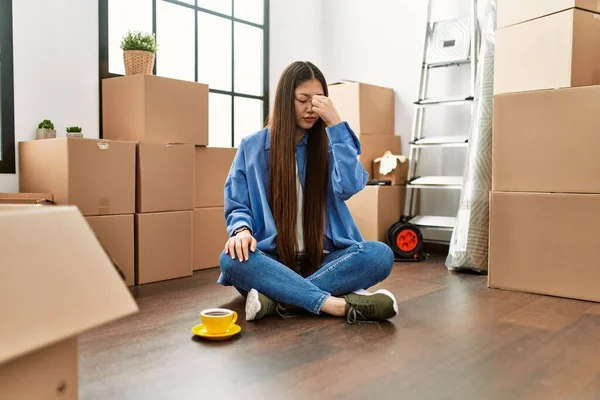 Genç Çinli kız yeni evinde yerde oturuyor yorgun burnu ve gözleri ovuşturuyor yorgunluk ve baş ağrısı hissediyor. Stres ve hüsran kavramı. 