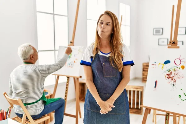 Hispanic Woman Wearing Apron Art Studio Making Fish Face Lips — стоковое фото