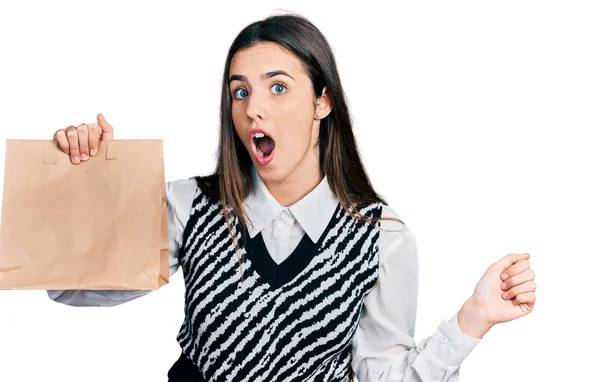 Young Brunette Teenager Holding Take Away Paper Bag Scared Amazed — ストック写真