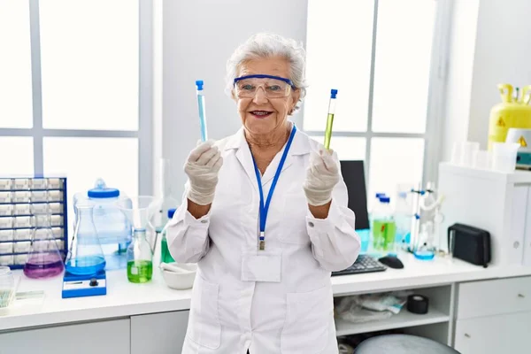 研究室で科学者の均一な保持試験管を身に着けているシニア白髪の女性 — ストック写真