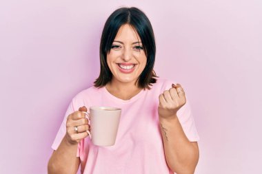 Bir fincan kahve içen genç İspanyol kadın gururla haykırıyor, zaferi ve başarıyı kutluyor. 