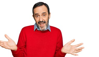 Orta yaşlı İspanyol bir adam, gündelik kıyafetler giyiyor, elleri ve kolları havada, kafası karışmış bir ifade takınıyor. şüphe kavramı. 