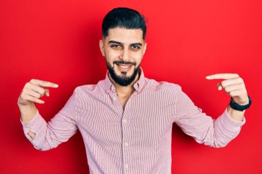 Sakallı, sıradan kırmızı tişörtlü, kendine güveni olan, kendini gururlu ve mutlu gösteren yakışıklı bir adam.. 