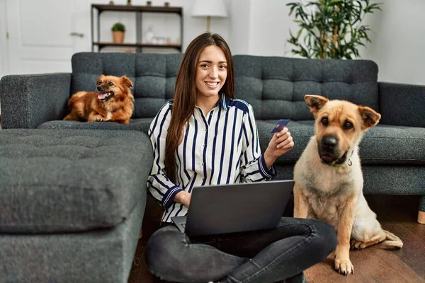 若いですヒスパニック女性使用してラップトップとクレジットカード座って床に犬とともに自宅 — ストック写真