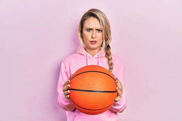 Hermosa Mujer Rubia Joven Sosteniendo Pelota Baloncesto Escéptico Nervioso Frunciendo —  Fotos de Stock