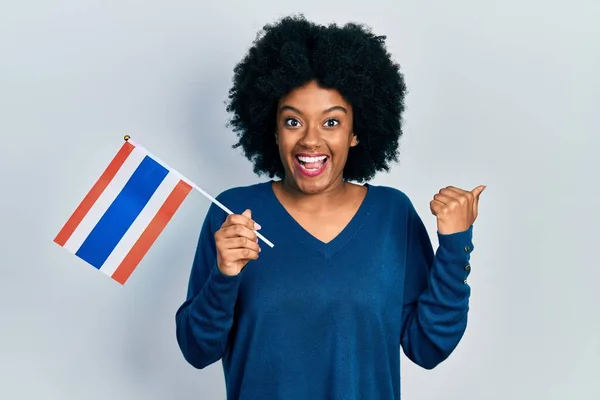 Young African American Woman Holding Thailand Flag Pointing Thumb Side — стоковое фото
