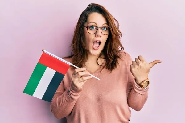 若いですCaucasian女性持っていますUnited Arab Emirates Flag指して親指へザサイド笑顔幸せとともにオープン口 — ストック写真