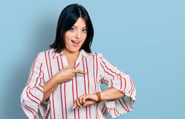 Gündelik giysiler giyen genç İspanyol kız saati, sabırsızlığı ve gecikmeyi izlemek için acele ediyor. 