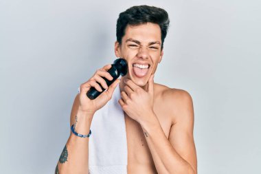 Genç bir İspanyol tıraş makinesi ile tıraş oluyor. Dilini çıkartıyor. Komik bir ifadeyle mutlu.. 