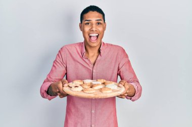 Genç Afrikalı Amerikalı çocuk elinde pasta tepsisiyle çılgınlığı kutluyor ve gözleri açık heyecanla haykırıyor.. 