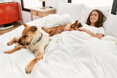 Genç İspanyol kadın yatak odasında köpeğe sarılıyor.