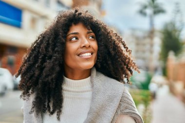 Genç Afrikalı Amerikalı kadın gülümseyerek şehirde mutlu mesut duruyor..