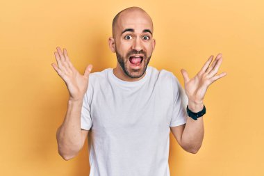 Sıradan beyaz tişört giyen genç kel adam çılgınlığı kutluyor ve başarıya hayret ediyor kolları açık ve gözleri açık heyecanla haykırıyor. Kazanan konsept 