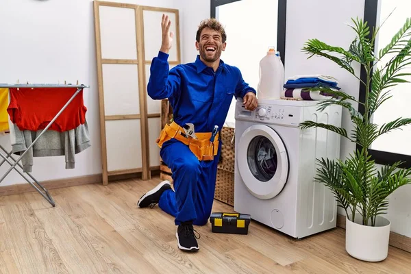 Çamaşır makinesinde çalışan genç İspanyol adam zaferi mutlu bir gülümseme ve kaldırılmış ellerle kazanan ifadeyle kutluyor. 