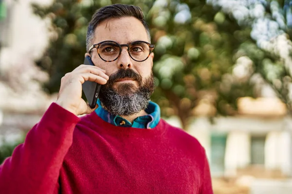 Ciddi bir suratı olan genç İspanyol bir yönetici şehirdeki akıllı telefondan konuşuyor..