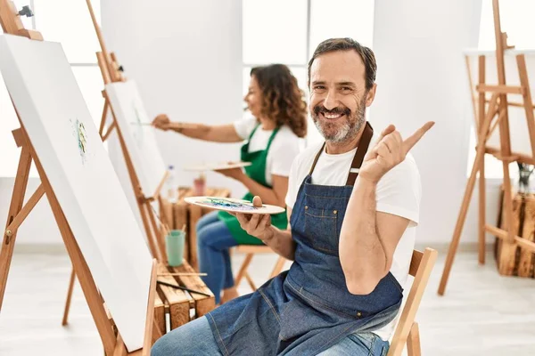 西班牙裔中年男人和艺术工作室的成熟女人笑容满面 手指手画脚 — 图库照片