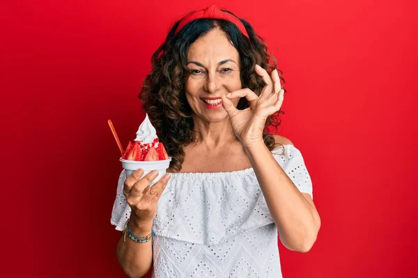 中世のヒスパニック系の女性は指でOkサインを行うイチゴのアイスクリームを食べます 笑顔優しいジェスチャー優れたシンボル — ストック写真