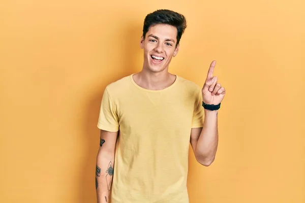 Joven Hombre Hispano Con Camiseta Amarilla Casual Apuntando Con Dedo —  Fotos de Stock