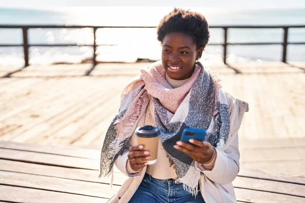 Afričanky Americká Žena Pomocí Smartphone Pití Kávy Sedí Lavičce Moře — Stock fotografie