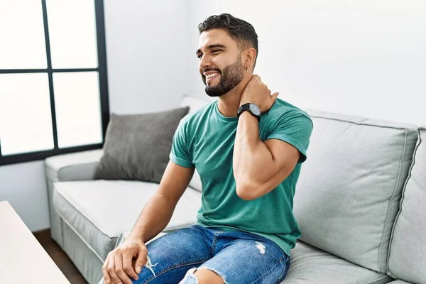 Jovem Árabe Homem Sofrendo Dor Pescoço Sentado Sofá Casa — Fotografia de Stock