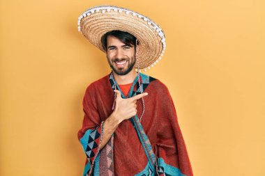 Meksika şapkası takan genç İspanyol bir adam. Yüzünde mutlu ve doğal bir ifadeyle elleri ve parmaklarıyla gülümsüyor. 