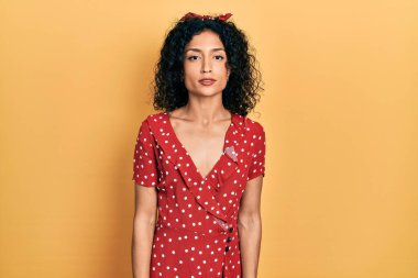 Yazlık elbise giyen genç Latin kız yüzünde ciddi bir ifadeyle rahatlamış. Basit ve doğal bir şekilde kameraya bakıyorsun.. 