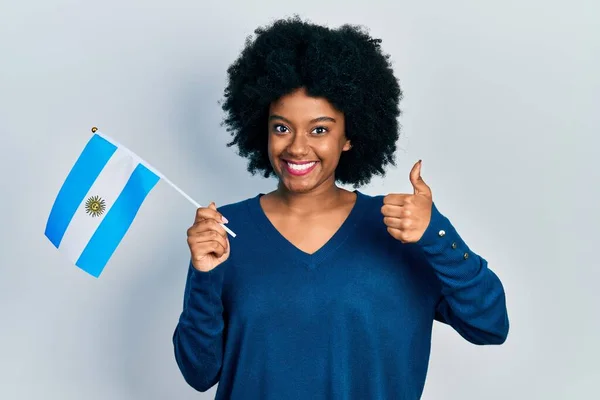 Joven Mujer Afroamericana Sosteniendo Bandera Argentina Sonriendo Feliz Positiva Pulgar —  Fotos de Stock