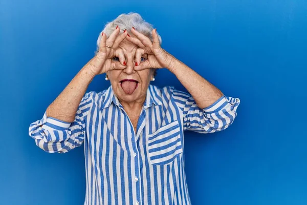 Oudere Vrouw Met Grijs Haar Staat Blauwe Achtergrond Doet Gebaar — Stockfoto