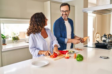 Orta yaşlı İspanyol çift mutfakta kendine güvenen yemekler pişiriyor.