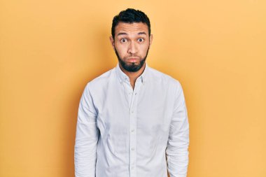 Sakallı, iş gömleği giyen, komik suratlı İspanyol bir adam. Havayla şişmiş ağız, çılgın bir ifade.. 