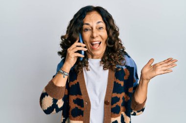 Orta yaşlı İspanyol bir kadın akıllı telefonda konuşuyor başarıyı mutlu bir gülümsemeyle kutluyor ve kazanan el kaldırarak ifade ediyor. 