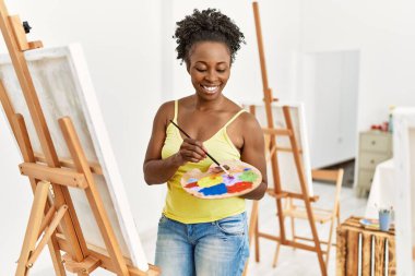 Genç Afrikalı Amerikalı sanatçı. Gülümsüyor. Sanat stüdyosunda mutlu çizimler..