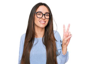 Gündelik kıyafetler ve gözlük takan genç İspanyol kız kameraya gülümseyip zafer işareti yapıyor. İki numara.. 