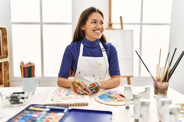 在艺术工作室里 年轻的黑发女人 手绘着彩绘 面带微笑地望向一边 有着自然的表情 充满自信地大笑 — 图库照片