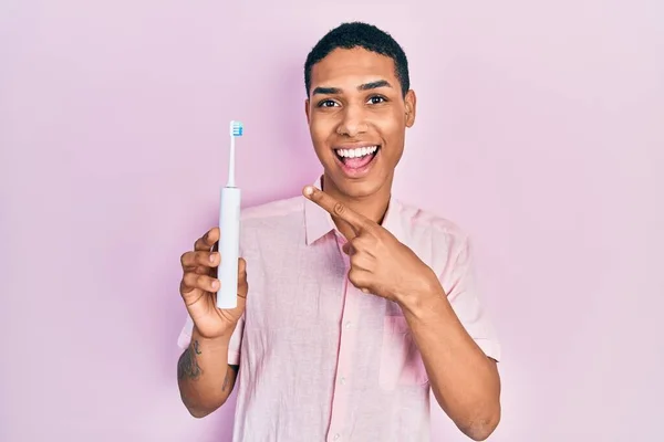 Jovem Afro Americano Segurando Escova Dentes Elétrica Sorrindo Feliz Apontando — Fotografia de Stock