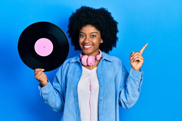 Kulaklık takan genç Afro-Amerikalı bir kadın. Plastik bir disk tutuyor. Gülümsüyor. 