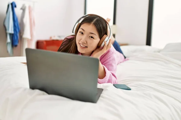 Młoda Chinka Korzystająca Laptopa Słuchawek Leżących Łóżku Sypialni — Zdjęcie stockowe