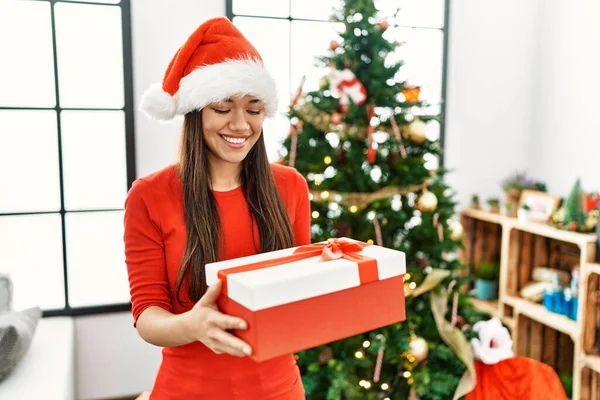 Young Latin Woman Holding Gift Standing Christmas Tree Home — Φωτογραφία Αρχείου