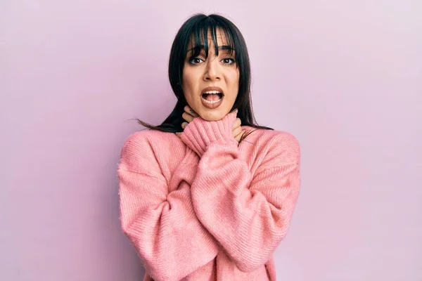 Young brunette woman with bangs wearing casual winter sweater shouting and suffocate because painful strangle. health problem. asphyxiate and suicide concept.