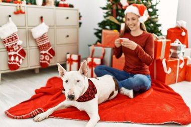 Kafkasyalı genç bir kadın evde köpekle oturup kahve içiyor.