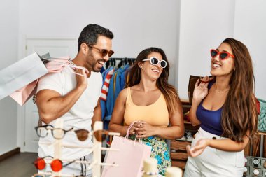 Bir grup İspanyol gülümseyen insan elbise mağazasında güneş gözlüğü denerken mutlu olurlar..