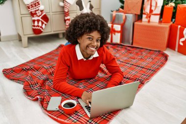 Genç Afro-Amerikalı kadın evde dizüstü bilgisayar kullanıyor.